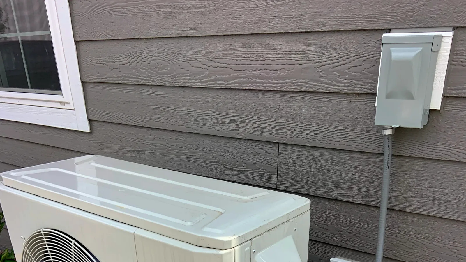 Heat pump unit installed on the exterior wall of a residential home